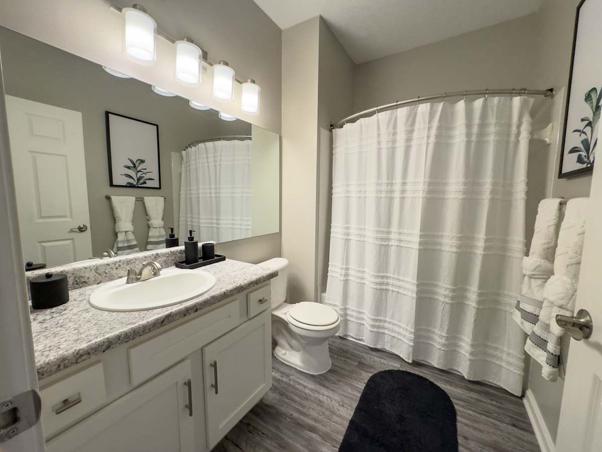 Model apartment: Enclave at Wolfchase bathroom with vanity, mirror and shower curtain - Memphis, TN